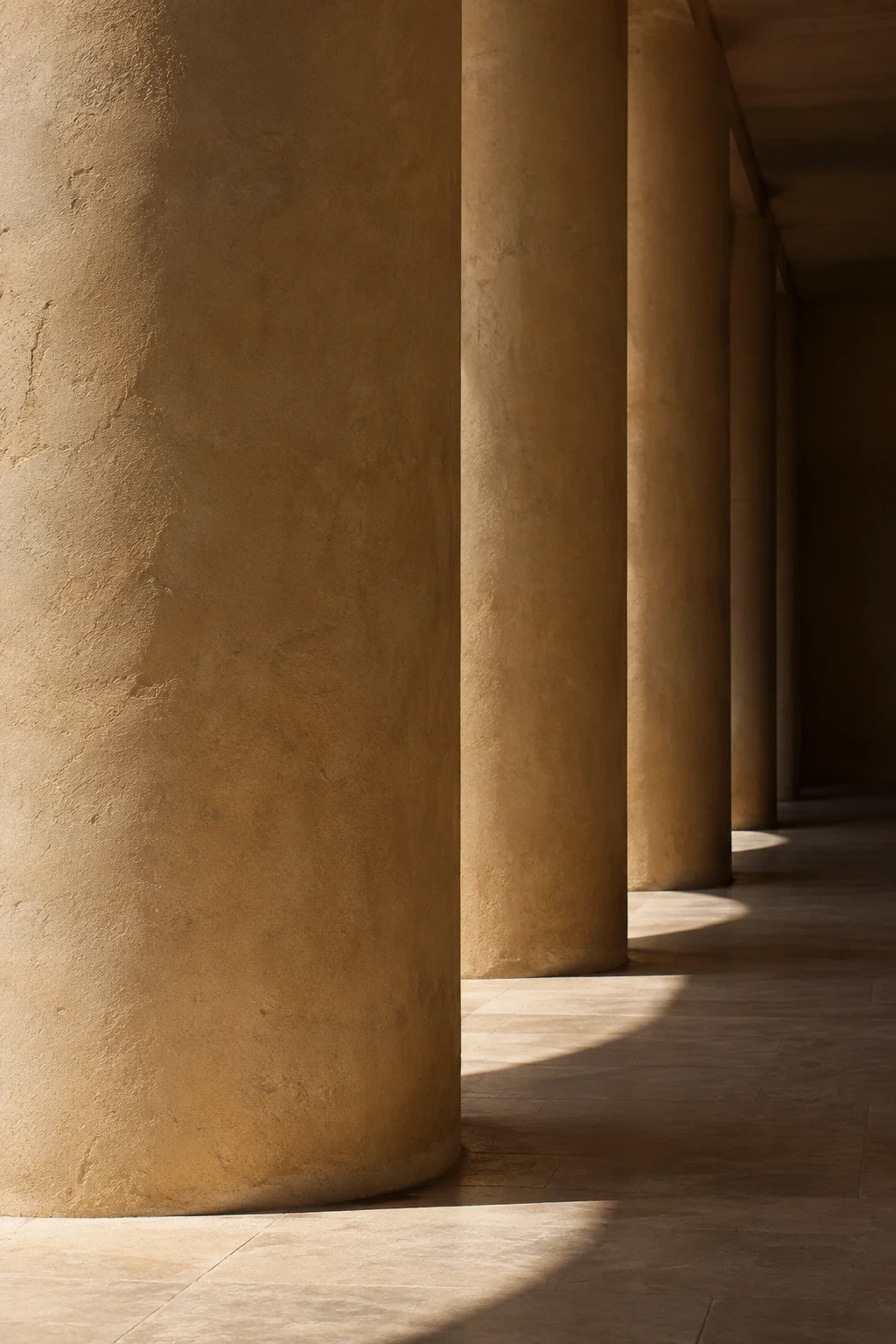 Ochre columns receding over a sunlit stone floor.